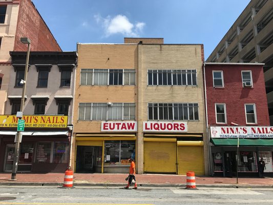 photograph of Eutaw Liquors, a storefront with bright yellow security roll up doors